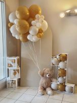 Anniversaire enfant pour ses 1 ans Un ours en peluche tient des ballons dorés et blancs près du chiffre 1.